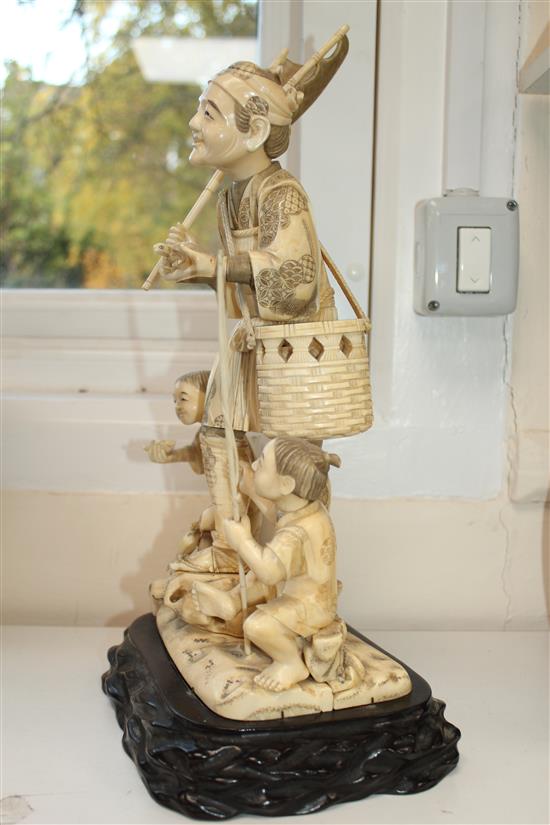 A large Japanese sectional walrus ivory okimono of a fisherman and two boys, early 20th century height including wood stand, 40cm